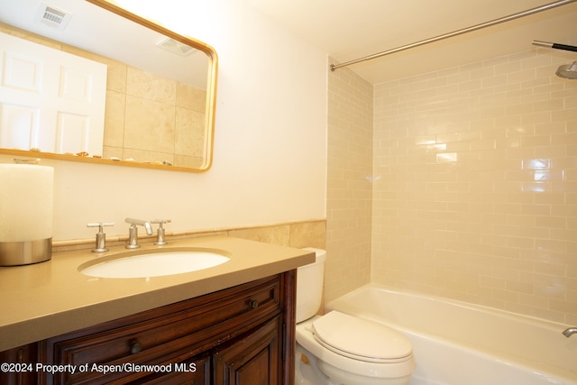 full bathroom featuring vanity, toilet, tile walls, and tiled shower / bath combo