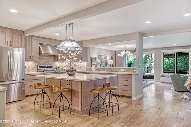 52 Harleston Grn Unit 38, Snowmass Village, CO 81615 - kitchen featuring stainless steel appliances, wall chimney exhaust hood, a chandelier, a breakfast bar area, and light countertops