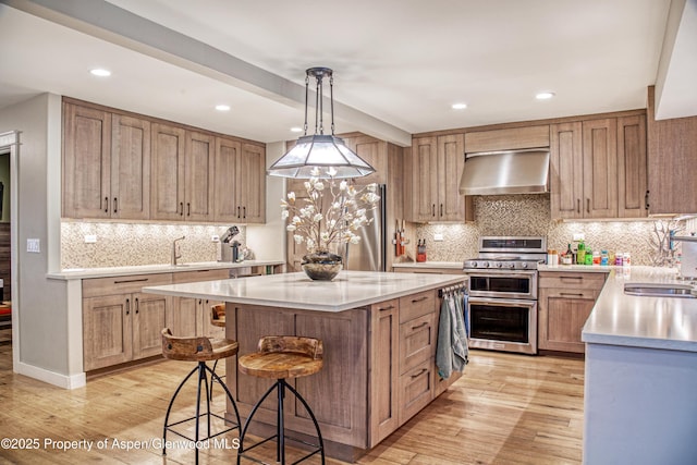 52 Harleston Grn Unit 38, Snowmass Village, CO 81615 - kitchen featuring appliances with stainless steel finishes, wall chimney range hood, light countertops, light wood-type flooring, and recessed lighting