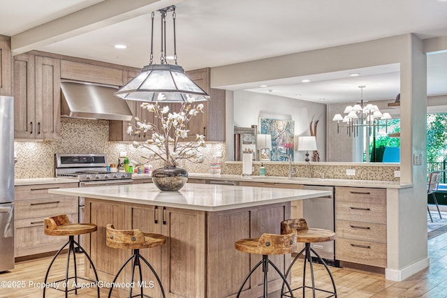 52 Harleston Grn Unit 38, Snowmass Village, CO 81615 - kitchen with wall chimney range hood, stainless steel appliances, a chandelier, light wood-style floors, and light brown cabinetry
