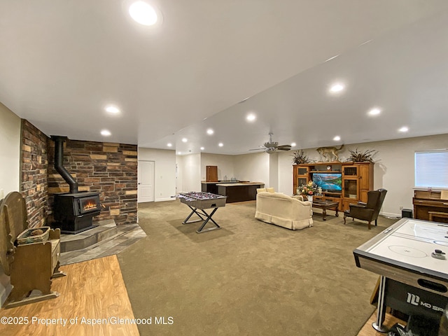 playroom featuring a wood stove, recessed lighting, carpet floors, a ceiling fan, and baseboards