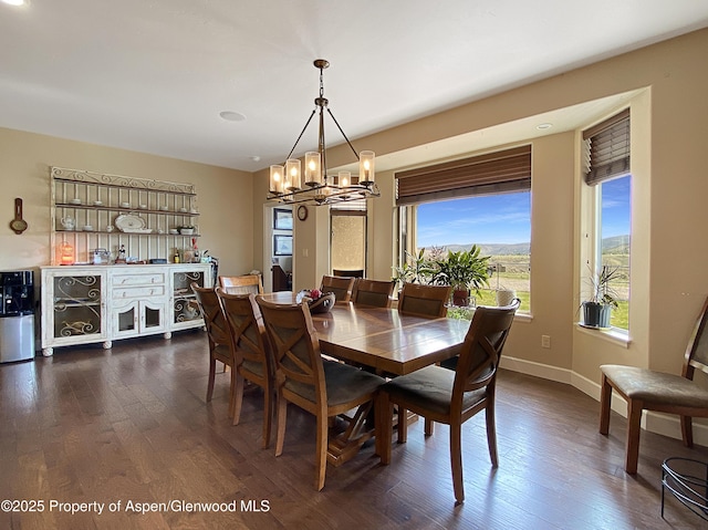 dining room with a chandelier, healthy amount of natural light, dark wood-style floors, and baseboards