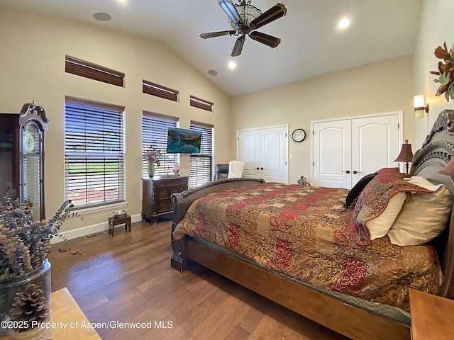 bedroom featuring two closets, high vaulted ceiling, wood finished floors, recessed lighting, and baseboards