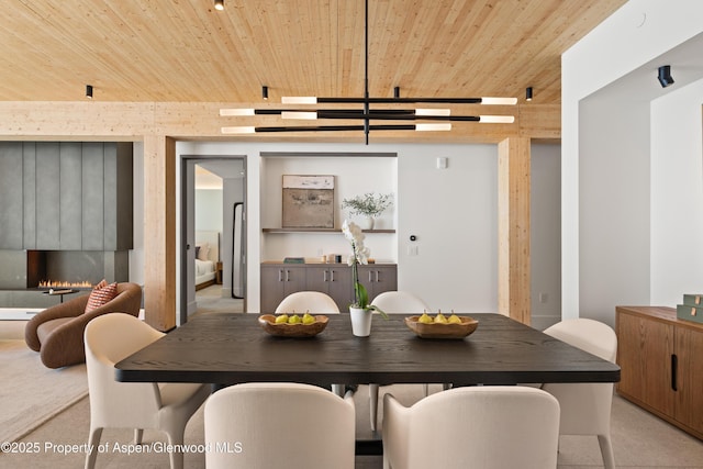 dining area with light carpet, a lit fireplace, and wood ceiling