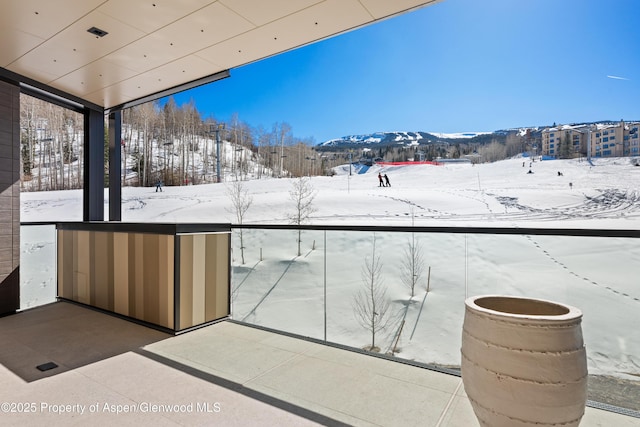 snow covered back of property with a mountain view