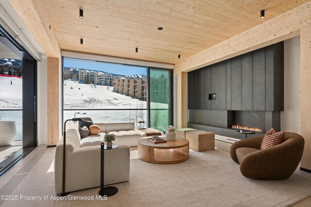 living room with a large fireplace, wooden ceiling, and floor to ceiling windows