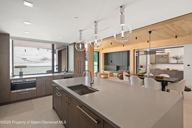 kitchen featuring dark brown cabinets, open floor plan, pendant lighting, modern cabinets, and a sink