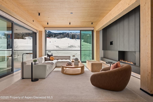 living room with a wealth of natural light, expansive windows, wooden ceiling, and a fireplace