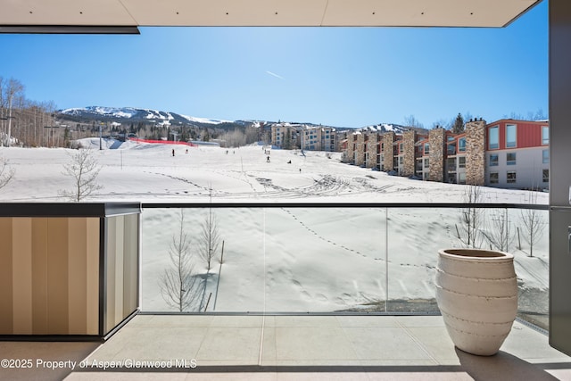 snow covered back of property featuring a mountain view