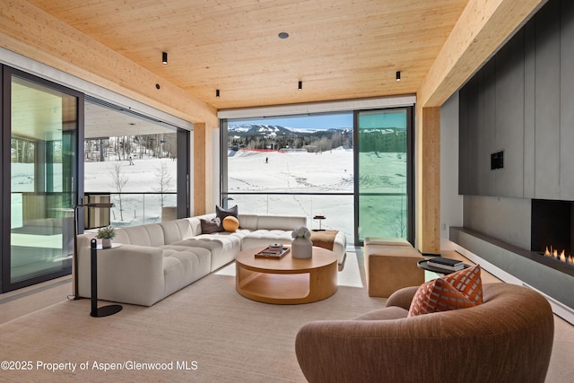 living area with expansive windows, wooden ceiling, and a fireplace