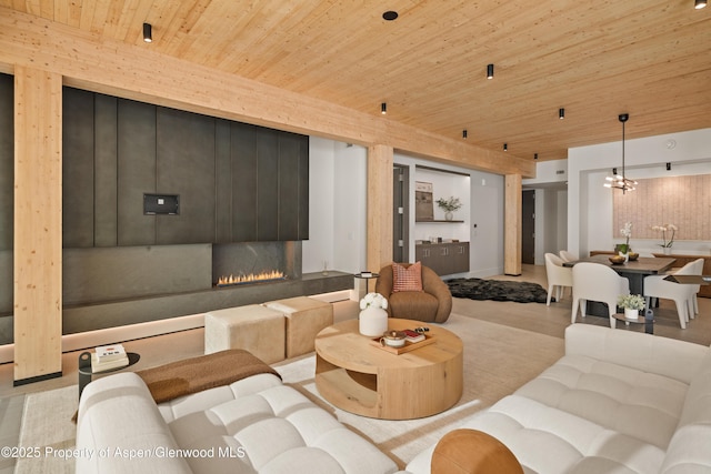 living room featuring wood ceiling, a chandelier, and a lit fireplace