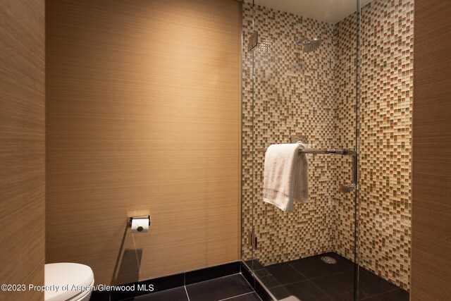 bathroom featuring tile patterned floors, toilet, and a shower with door