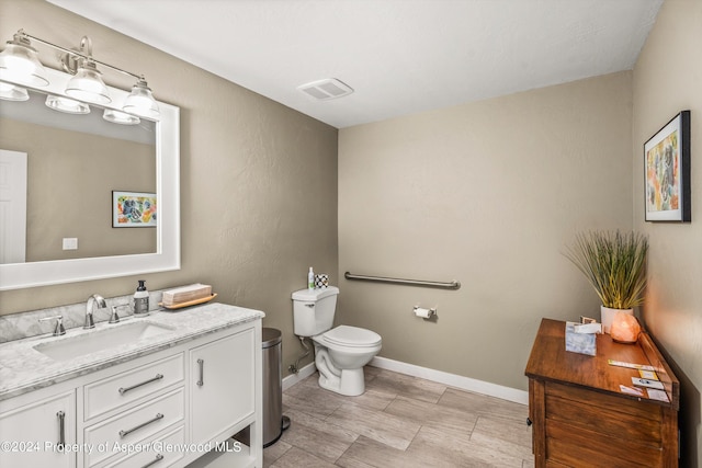 bathroom featuring visible vents, baseboards, toilet, and vanity