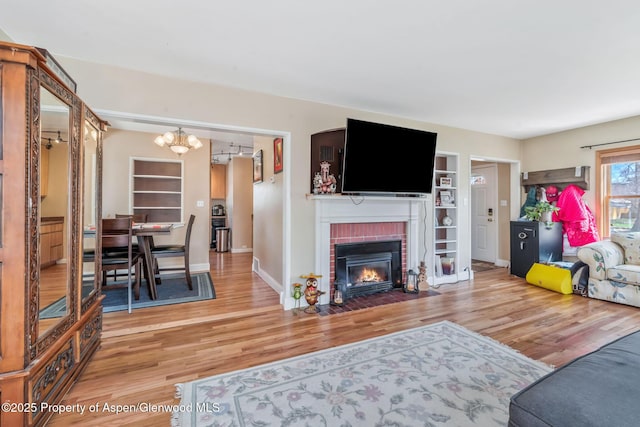 668 Taylor St, Craig, CO 81625 - living room featuring wood finished floors, a brick fireplace, a notable chandelier, baseboards, and built in shelves
