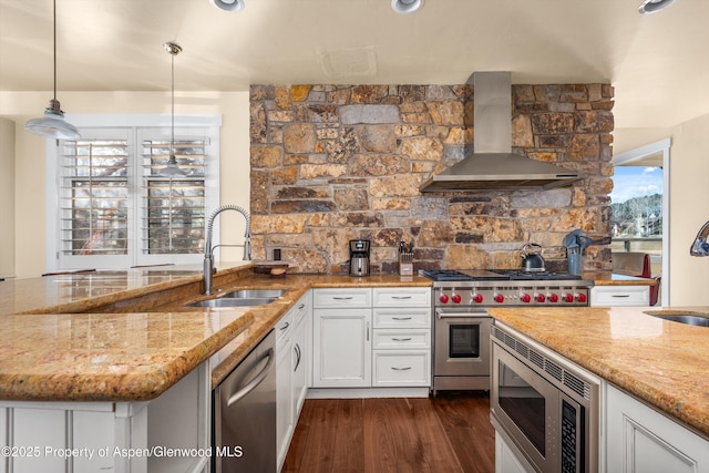 kitchen featuring appliances with stainless steel finishes, light stone counters, dark wood-style flooring, wall chimney range hood, and a sink