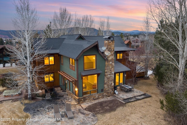 back of house featuring a mountain view, a chimney, and a patio