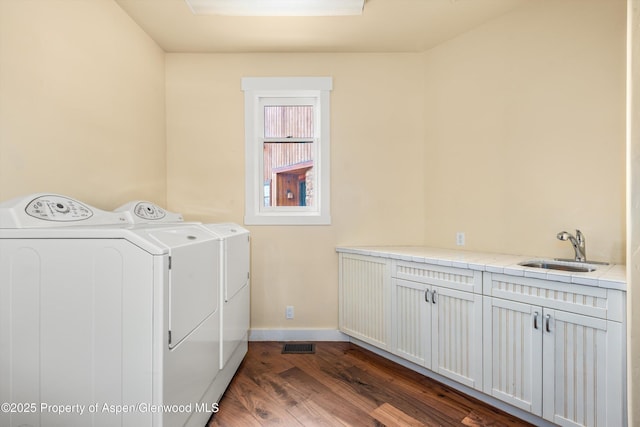 laundry area with cabinet space, baseboards, dark wood-style floors, independent washer and dryer, and a sink