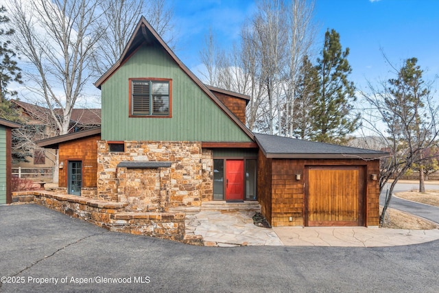 chalet / cabin with an attached garage and stone siding