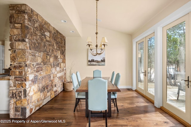 dining room with baseboards, lofted ceiling, wood finished floors, french doors, and a notable chandelier