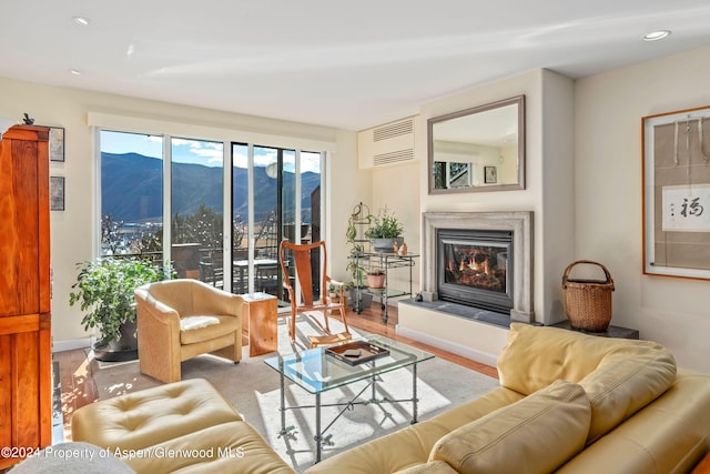 living room with a wall mounted air conditioner, a mountain view, and light hardwood / wood-style floors