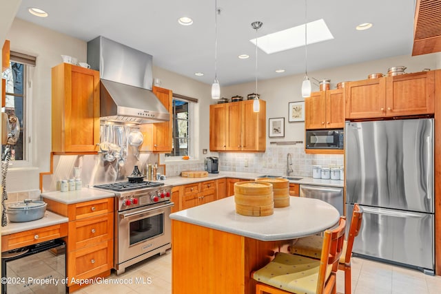 kitchen with a skylight, wall chimney exhaust hood, decorative backsplash, a kitchen island, and stainless steel appliances