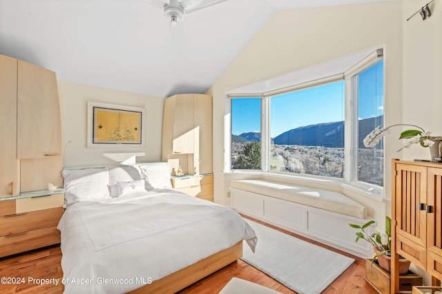 bedroom featuring a mountain view, light hardwood / wood-style floors, ceiling fan, and vaulted ceiling