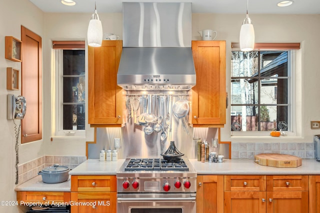 kitchen featuring wall chimney range hood, pendant lighting, and high end stainless steel range oven