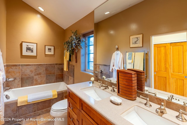 bathroom featuring tile patterned flooring, vanity, toilet, and tiled bath