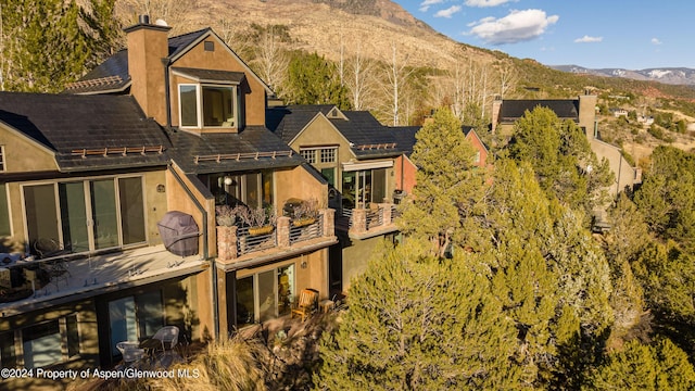 back of property with a mountain view and a balcony