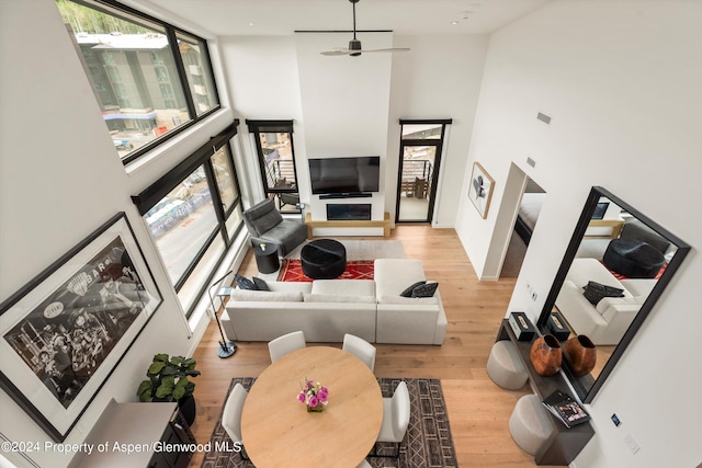 living room with ceiling fan, light hardwood / wood-style floors, and a high ceiling