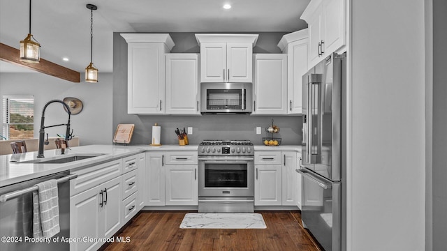 kitchen featuring dark wood finished floors, a sink, hanging light fixtures, appliances with stainless steel finishes, and white cabinetry