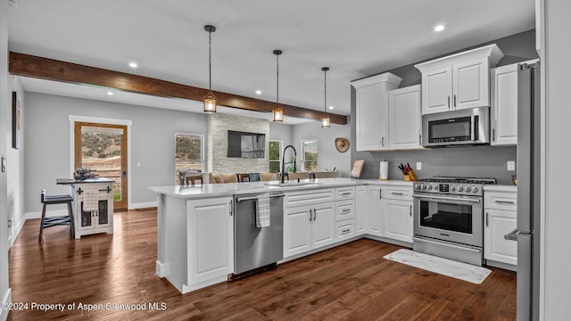 kitchen featuring a sink, stainless steel appliances, beam ceiling, and a peninsula