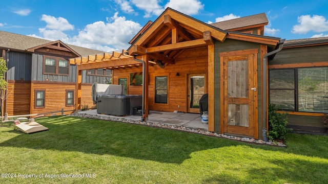 back of property with a yard, a hot tub, and a patio