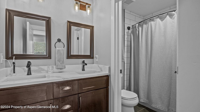 bathroom featuring double vanity, visible vents, toilet, and a sink