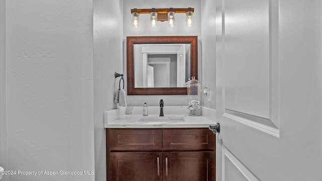 half bathroom featuring vanity and a textured wall