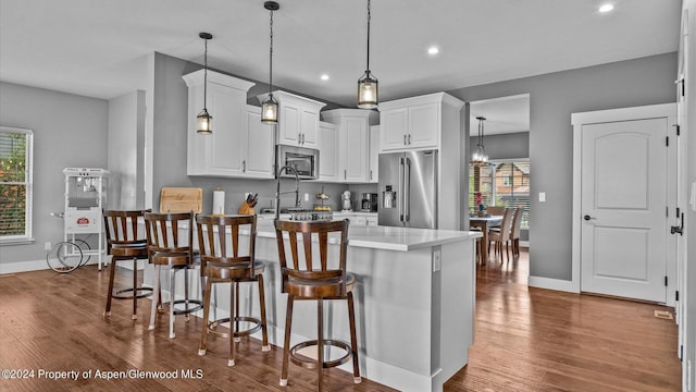 kitchen featuring stainless steel appliances, a kitchen bar, a peninsula, and wood finished floors