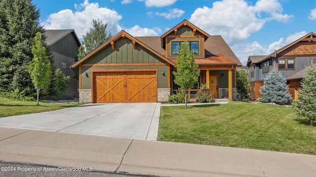 craftsman-style house featuring a porch, concrete driveway, a front yard, a garage, and stone siding