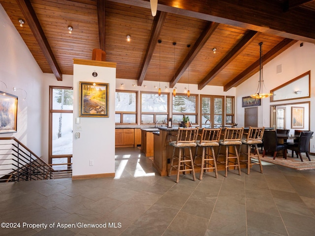 kitchen featuring a kitchen bar, beam ceiling, decorative light fixtures, and wood ceiling