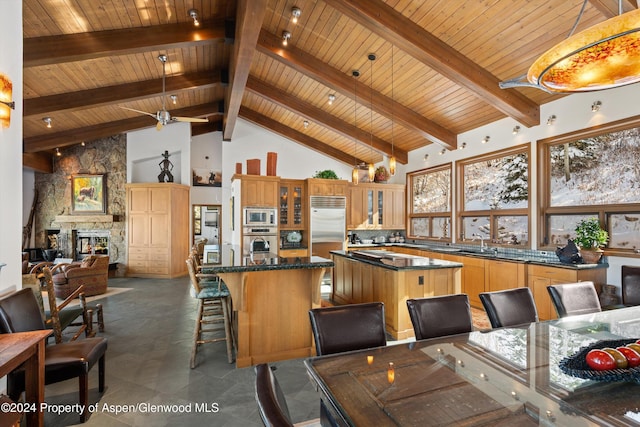 kitchen with built in appliances, decorative light fixtures, a kitchen island, and high vaulted ceiling