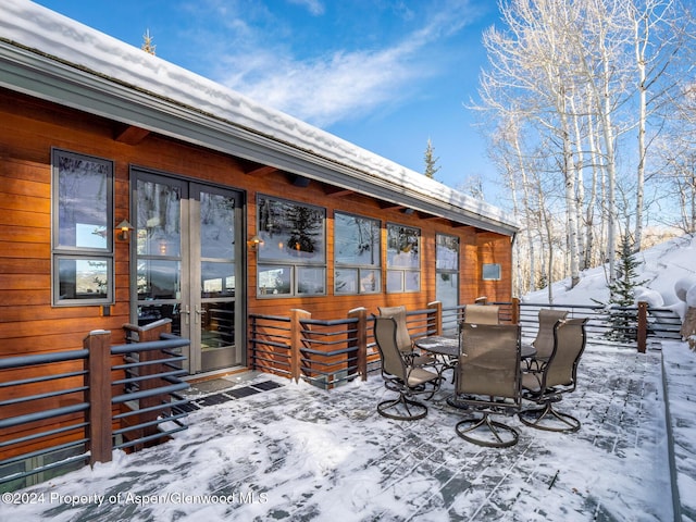 snow covered deck featuring french doors