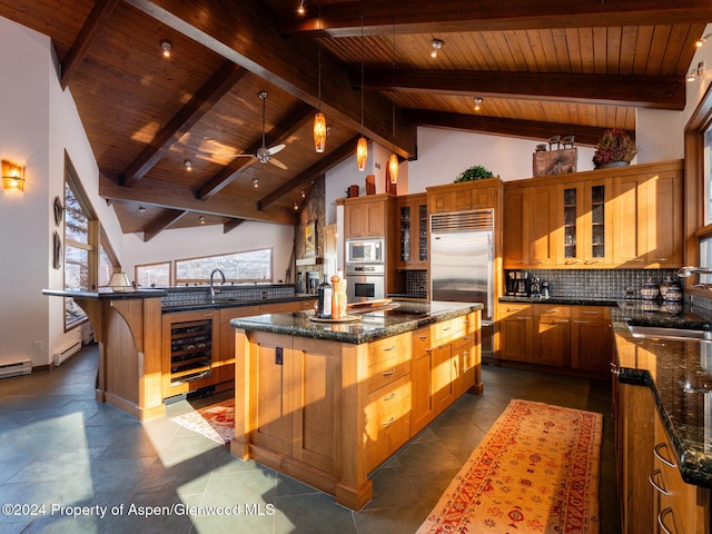 kitchen with sink, wine cooler, beamed ceiling, built in appliances, and a kitchen island