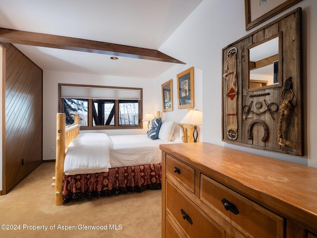 bedroom featuring beam ceiling, light carpet, and wooden walls