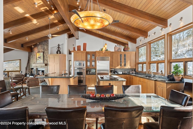 dining space featuring beam ceiling, a stone fireplace, high vaulted ceiling, and wooden ceiling