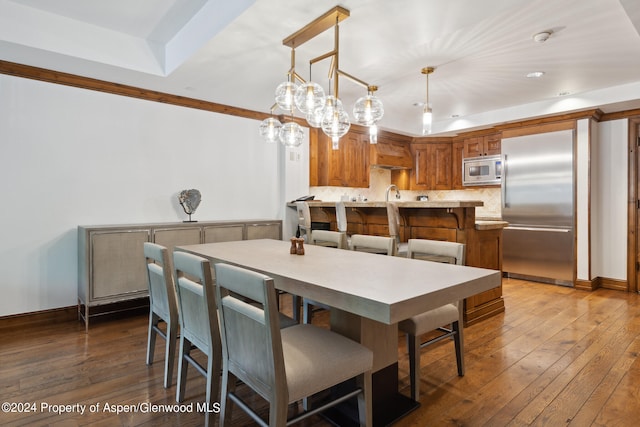 dining area featuring a tray ceiling, sink, and dark wood-type flooring