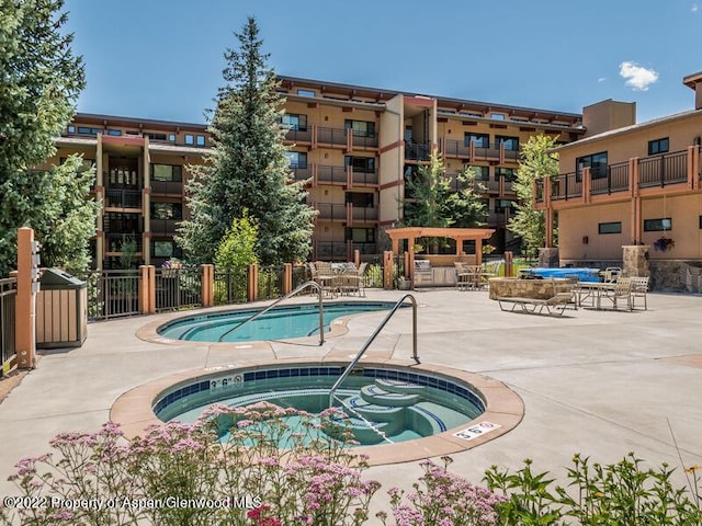 community pool featuring a hot tub, a patio, and fence