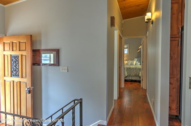 corridor featuring baseboards, lofted ceiling, dark wood-style flooring, wood ceiling, and an upstairs landing