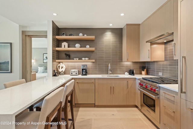 kitchen with a kitchen bar, kitchen peninsula, sink, and range hood