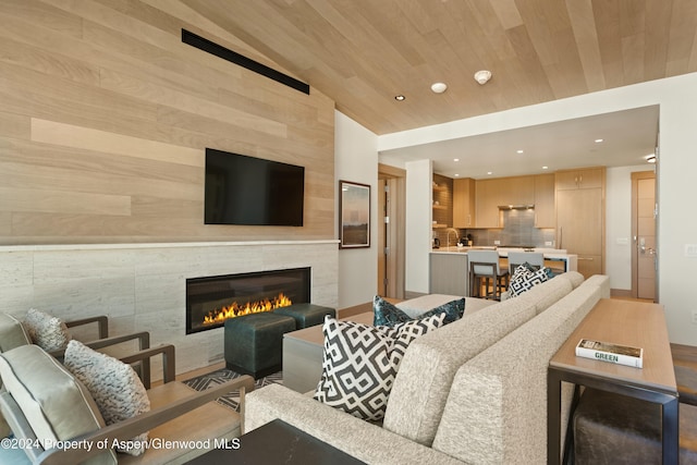 living room featuring a tile fireplace, vaulted ceiling, wooden walls, and wood ceiling