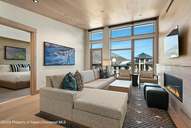 living room with a fireplace, a healthy amount of sunlight, wooden ceiling, and wood-type flooring