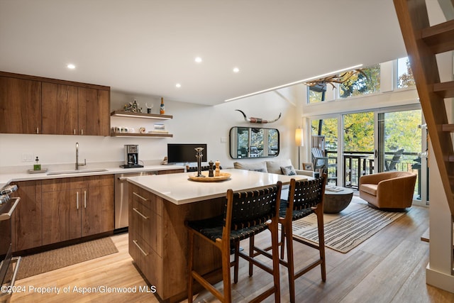 kitchen featuring sink, a kitchen island, stainless steel appliances, and light hardwood / wood-style flooring